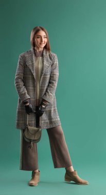 Deri eldivenli ve yeşil arka planda ceketli güzel bir kadın.