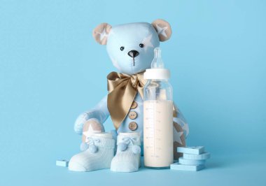 Mavi arka planda bebek için süt şişeli oyuncak ayı