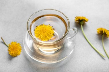 Gri arkaplanda bir bardak sağlıklı karahindiba çayı.