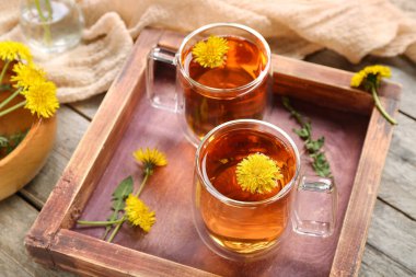 Tahta zemin üzerinde cam bardaklar dolusu sağlıklı karahindiba çayı.