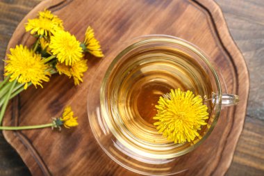 Tahta arka planda cam bardak sağlıklı karahindiba çayı.