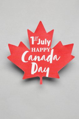 Kağıt akçaağaç yaprağı ve gri arkaplan üzerinde 1 Temmuz Mutlu Kanadalılar Günü