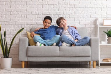 Evdeki kanepede kucaklaşan sevimli çocuklar.