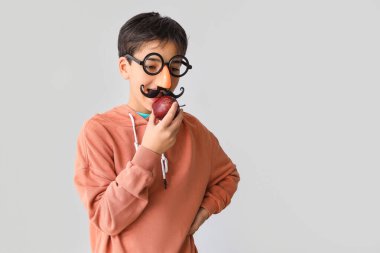 Hafif arka planda elmayla kılık değiştirmiş komik bir çocuk. Çocuk Bayramı kutlaması