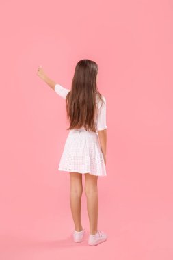 Pembe arka planda tebeşirle çizen küçük bir kız. Çocuk Bayramı kutlaması