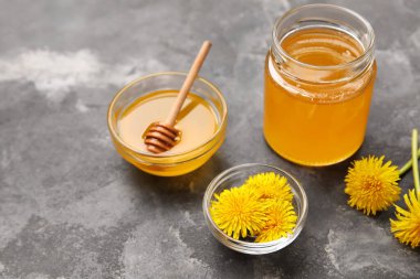 Kavanoz ve kase koyu grunge arka planda karahindiba balı.