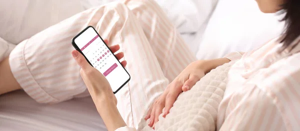 Młoda Kobieta Trzyma Telefon Komórkowy Otwartym Kalendarzem Menstruacyjnym Ekranie Sypialni — Zdjęcie stockowe