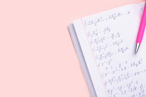 Copybook with maths formulas and pen on pink background