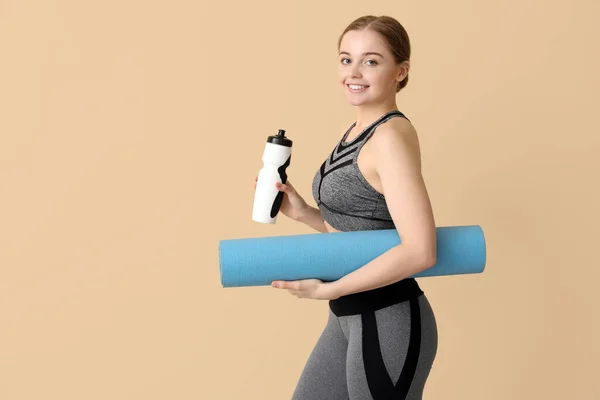 Sportliche Junge Frau Mit Yogamatte Und Wasserflasche Auf Beigem Hintergrund — Stockfoto