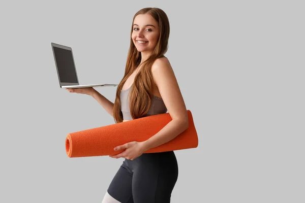 Sportliche Junge Frau Mit Yogamatte Und Laptop Auf Grauem Hintergrund — Stockfoto