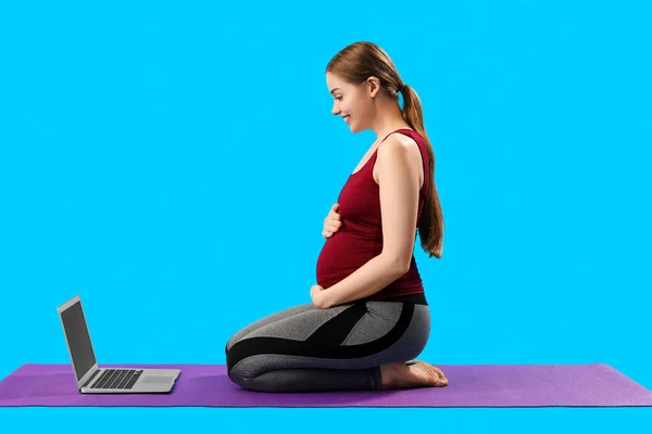 Mujer Joven Embarazada Con Portátil Haciendo Yoga Sobre Fondo Azul —  Fotos de Stock