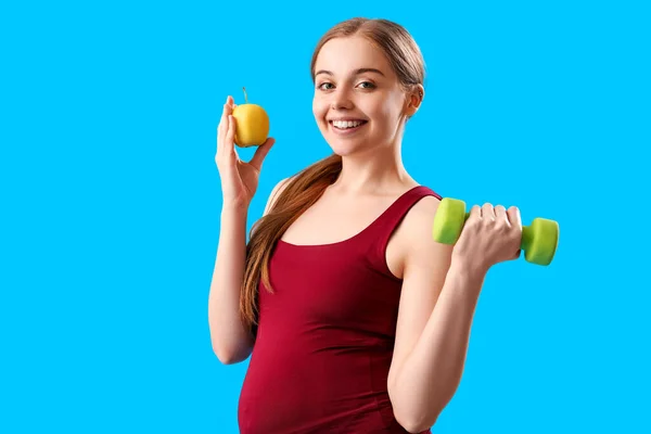Sportliche Schwangere Mit Apfel Und Hantel Auf Blauem Hintergrund — Stockfoto