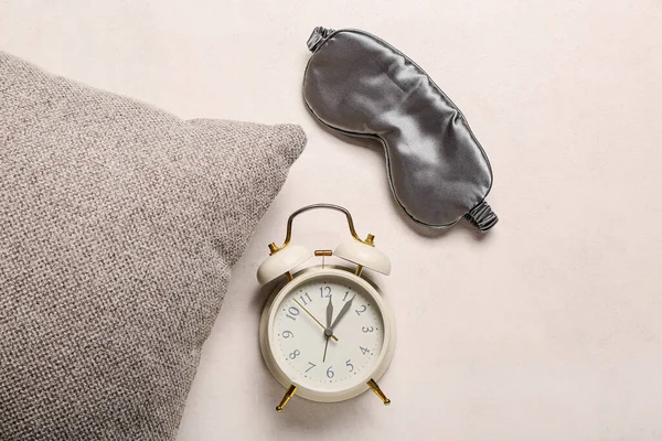 Sleeping mask with alarm clock and pillow on light background