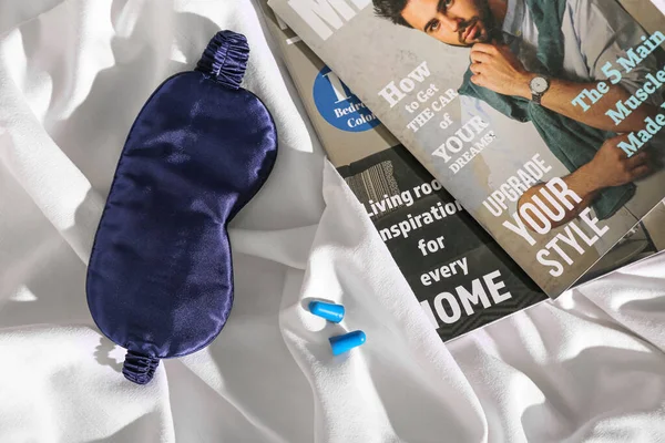 Schlafmaske Mit Zeitschriften Und Ohrstöpseln Auf Dem Bett — Stockfoto