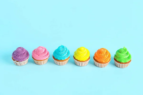 Tasty colorful cupcakes on blue background