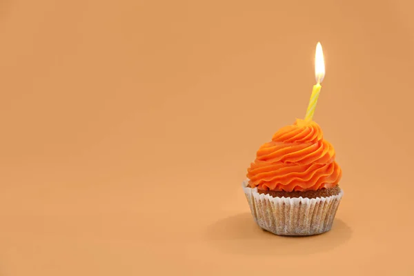 オレンジの背景に誕生日キャンドル付きおいしいカップケーキ — ストック写真