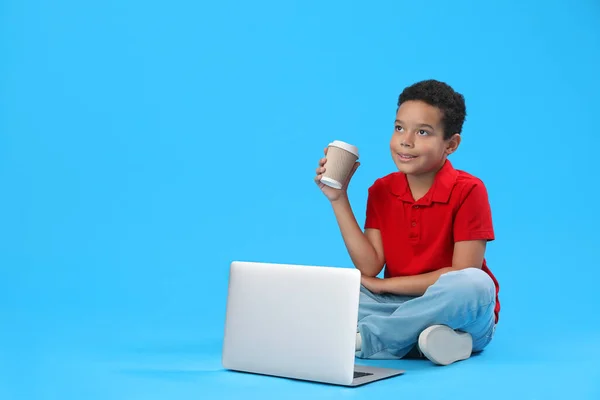 Mały Afroamerykanin Kubkiem Kakao Laptopem Niebieskim Tle Obchody Dnia Dziecka — Zdjęcie stockowe