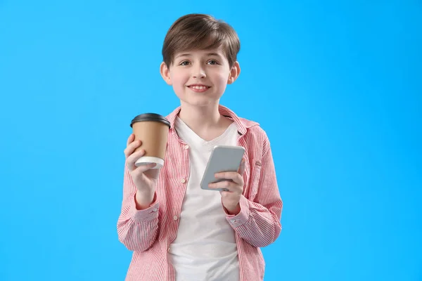 Egy Kisfiú Egy Csésze Kakaóval Mobiltelefonnal Kék Háttérrel Gyermeknapi Ünnepség — Stock Fotó