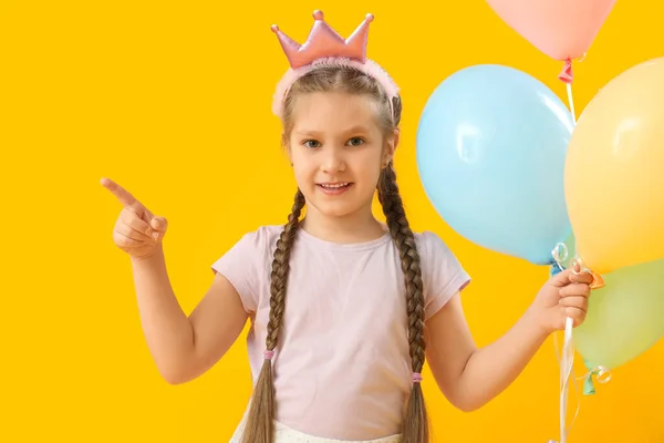 Sarı Arka Plandaki Bir Şeyi Gösteren Balonlu Küçük Kız Çocuk — Stok fotoğraf