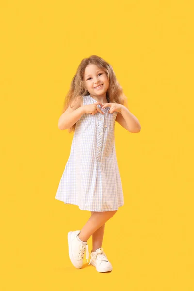 小女孩双手插在黄色的背景上 心情舒畅 儿童节庆祝活动 — 图库照片