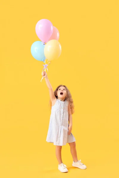 带着黄色背景气球的小女孩儿童节庆祝活动 — 图库照片