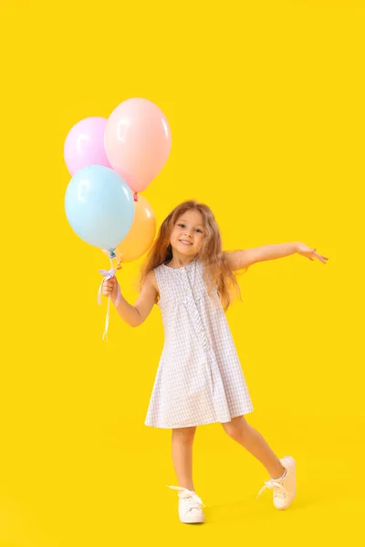 带着黄色背景气球的小女孩儿童节庆祝活动 — 图库照片