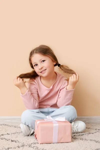 Mała Dziewczynka Prezentem Siedząca Przy Beżowej Ścianie Obchody Dnia Dziecka — Zdjęcie stockowe