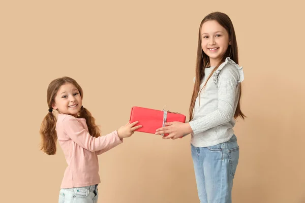 小女孩带着米色背景的礼物问候她的姐姐 儿童节庆祝活动 — 图库照片