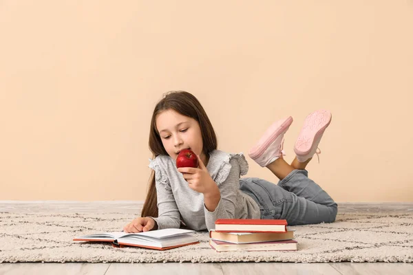 Bej Duvarın Yanında Elma Okuma Kitabı Olan Küçük Bir Kız — Stok fotoğraf