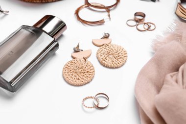 Güzel kadın aksesuarları ve beyaz arka planda bir şişe parfümü olan kompozisyon, yakın plan.