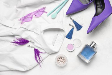 Şık kadın aksesuarları, kozmetik ürünleri, açık arkaplanda giysiler ve topuklu ayakkabılar.