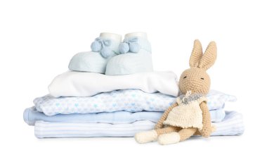 Bebek kıyafetleri yığını ve beyaz arka planda örülmüş oyuncak.