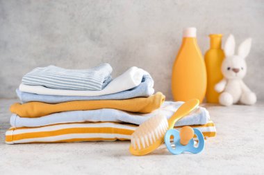 Bebek kıyafetleri, saç fırçası ve emzik yığını.