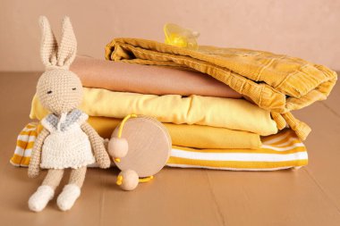 Bebek kıyafetleri, emzik ve oyuncaklar renkli ahşap masa.