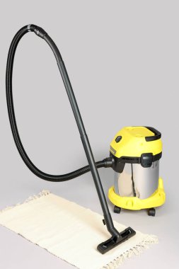 Gri arka planda halısı olan elektrikli süpürge.