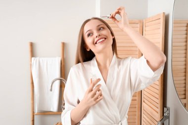 Evde saç dökülmesi tedavisi için serum kullanan genç bir kadın.