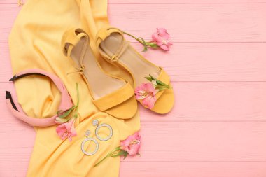 Renkli ahşap arka planda şık kadın aksesuarları, ayakkabıları ve alstromerya çiçekleriyle kompozisyon