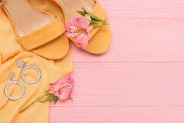 Güzel küpeler, ayakkabılar ve ahşap arka planda alstromerya çiçekleri