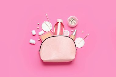 Makyaj ürünleri ve pembe arka planda deniz suyu bulunan kozmetik çanta.