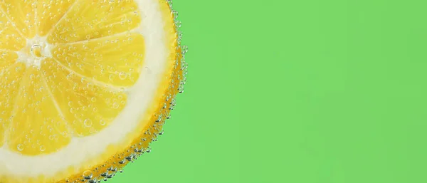 stock image Lemon slice in water against green background with space for text, closeup