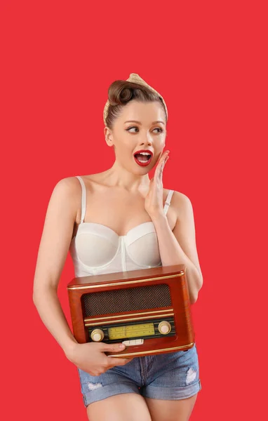 令人惊讶的年轻女子带着红色背景的复古收音机 — 图库照片