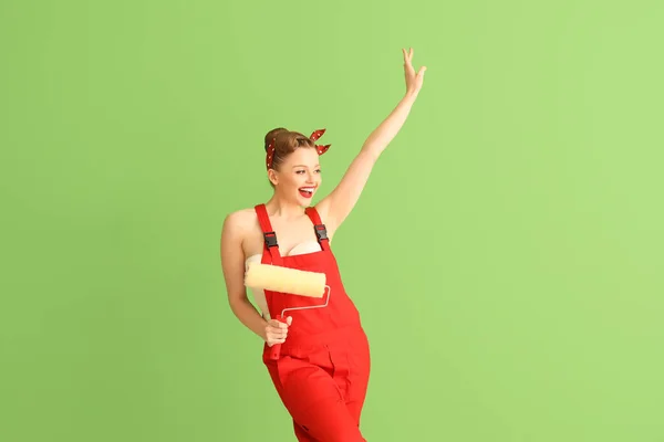 Kırmızı Üniformalı Yeşil Arka Planda Boya Silindirli Genç Bir Kadın — Stok fotoğraf