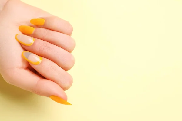 Woman with press-on nails on yellow background, closeup