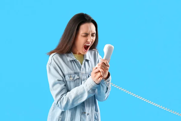 Mujer Joven Gritando Enojado Con Receptor Teléfono Sobre Fondo Azul —  Fotos de Stock