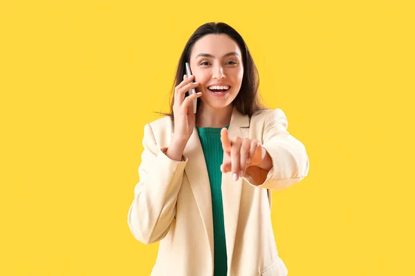 Щаслива Молода Жінка Розмовляє Телефону Вказує Глядача Жовтому Тлі — стокове фото