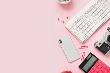 Pembe zemin üzerinde klavye, cep telefonu ve fotoğraf makinesi olan kompozisyon