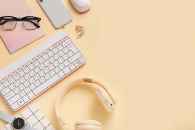 Bej arka planda klavye, kulaklık, cep telefonu ve gözlüklü kompozisyon