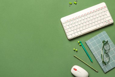 Yeşil arkaplanda klavye, gözlük ve defter ile kompozisyon