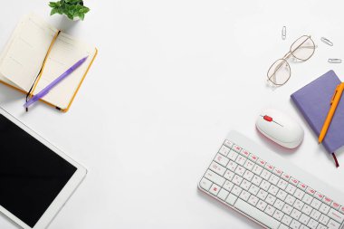 Beyaz arkaplanda tablet bilgisayar, klavye, defter ve gözlük ile kompozisyon