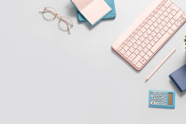 Mavi arkaplanda klavye, gözlük, not defteri ve hesap makinesi ile kompozisyon